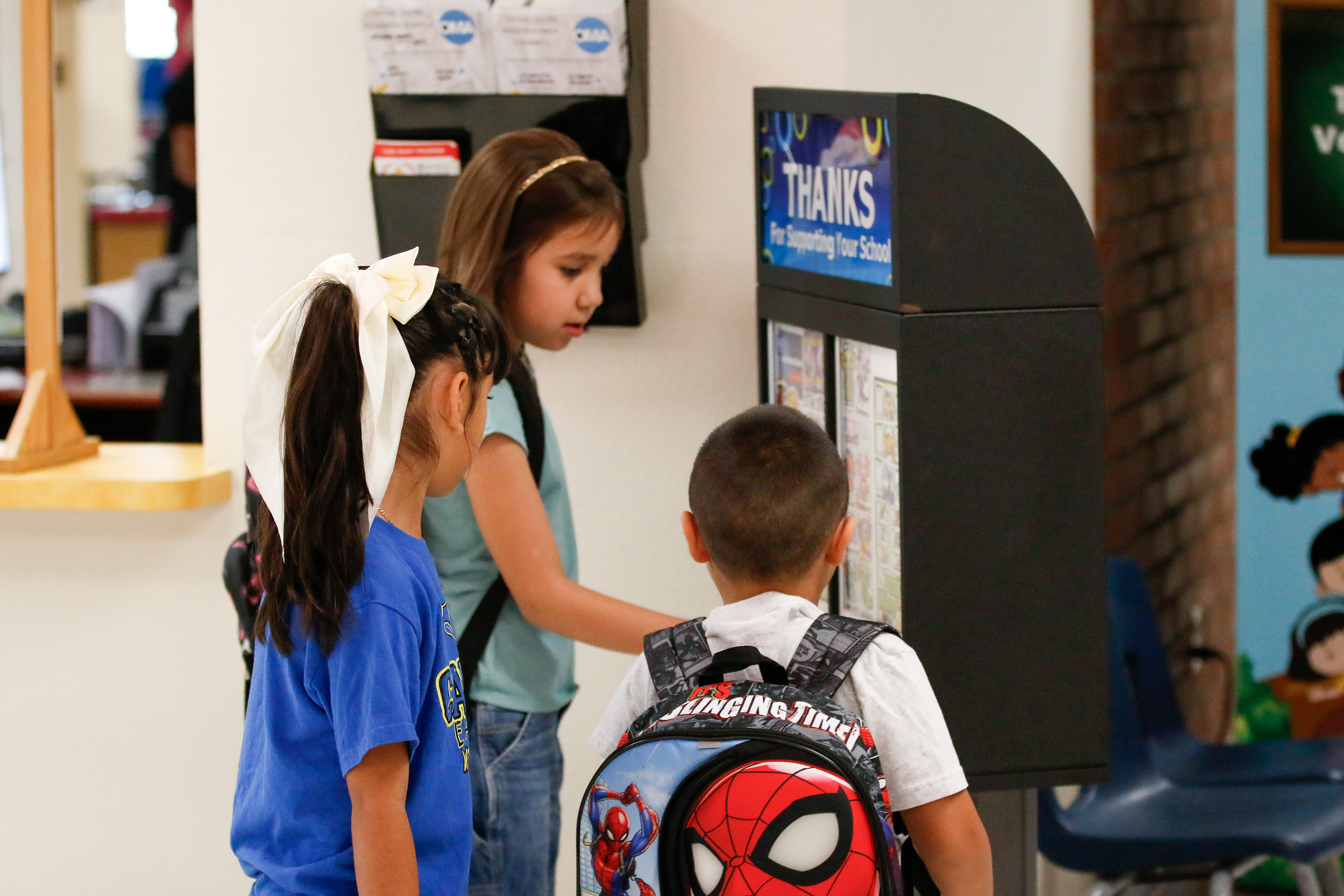 Three students gather around a small vending machine