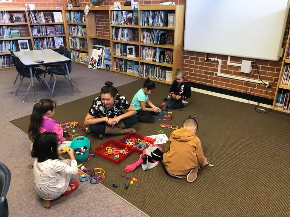 Students sit on the floor playing with educational toys